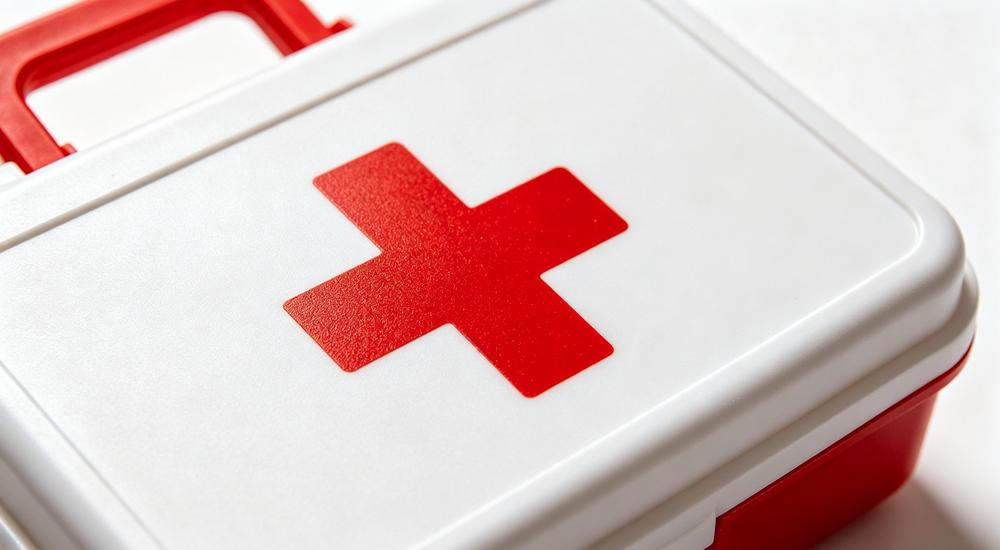 Close-up detail shot of red cross emblem on white and red hard shell first aid kit showing smooth plastic texture