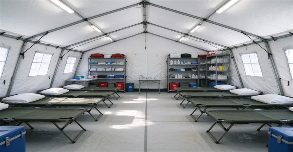 Wide view of responders treating patients inside white medical emergency tent showing mass casualty field treatment